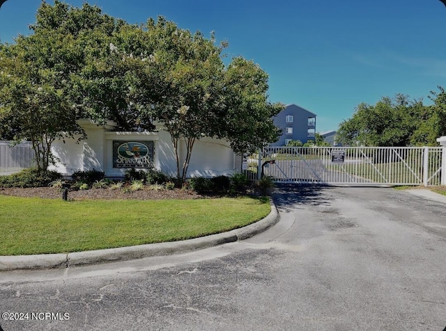 view of front facade featuring aphalt driveway, a front yard, a gate, and fence