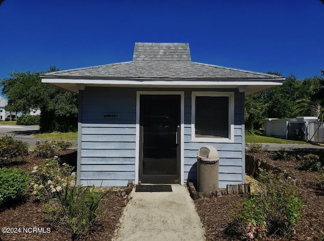 view of exterior entry featuring roof with shingles