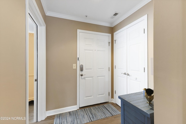 foyer entrance with baseboards, visible vents, wood finished floors, and ornamental molding