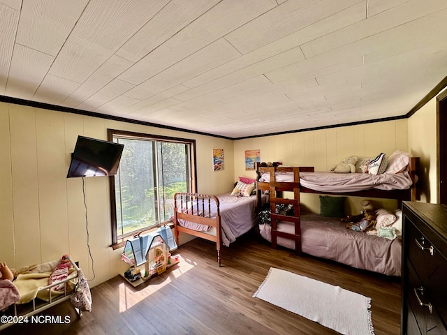 bedroom with wood walls, hardwood / wood-style floors, and ornamental molding