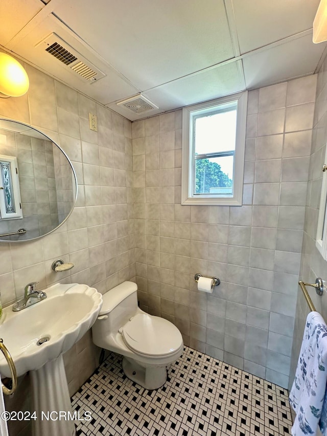 bathroom featuring tile patterned flooring, toilet, and tile walls