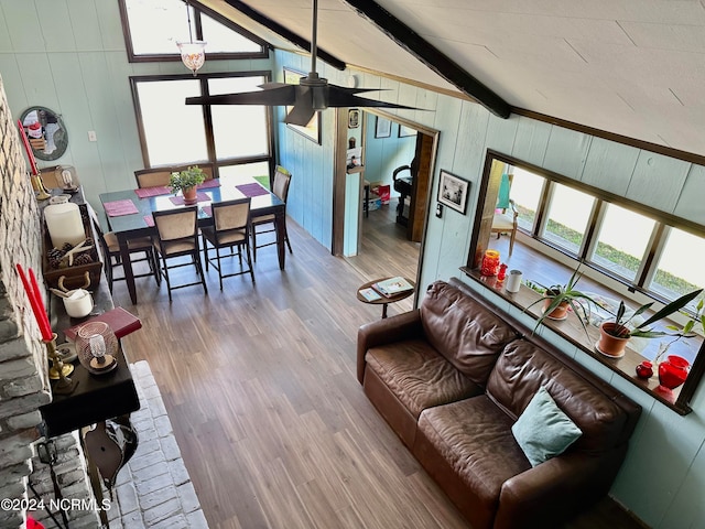 living room featuring vaulted ceiling with beams, ceiling fan, hardwood / wood-style floors, and wood walls