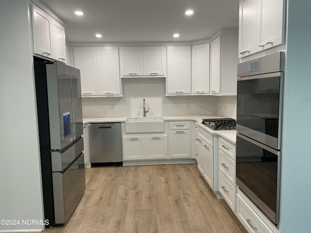 kitchen featuring a sink, light countertops, stainless steel appliances, and white cabinetry
