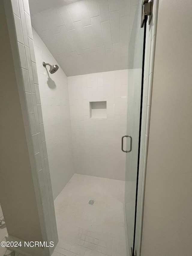 full bathroom featuring a shower stall and lofted ceiling