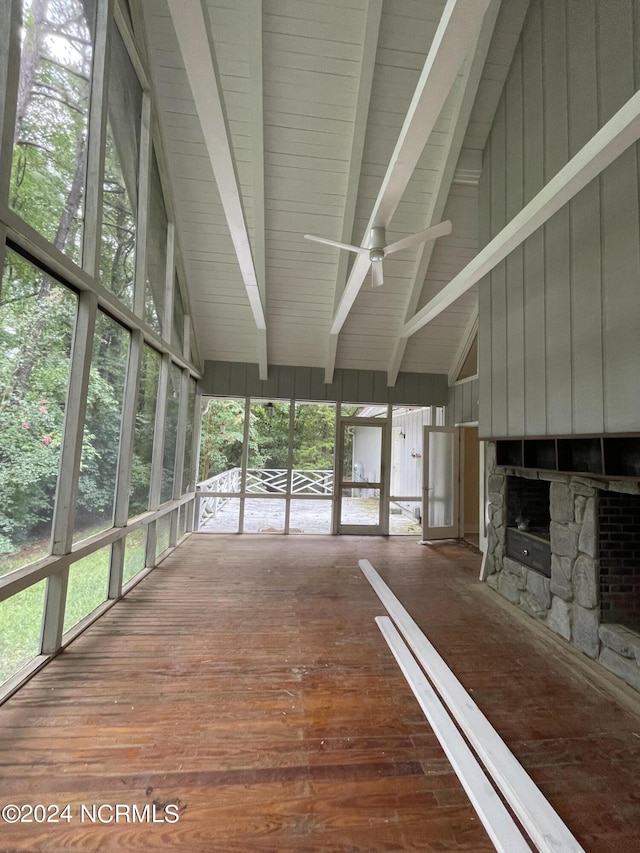 unfurnished sunroom with ceiling fan, beam ceiling, and a fireplace