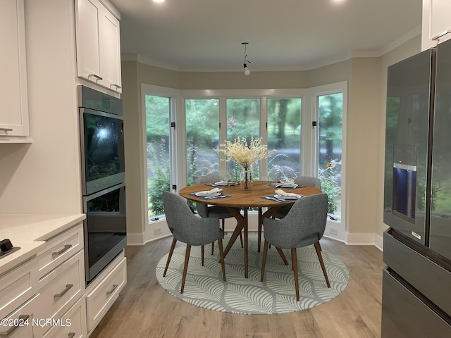 dining space featuring baseboards, ornamental molding, and light wood finished floors
