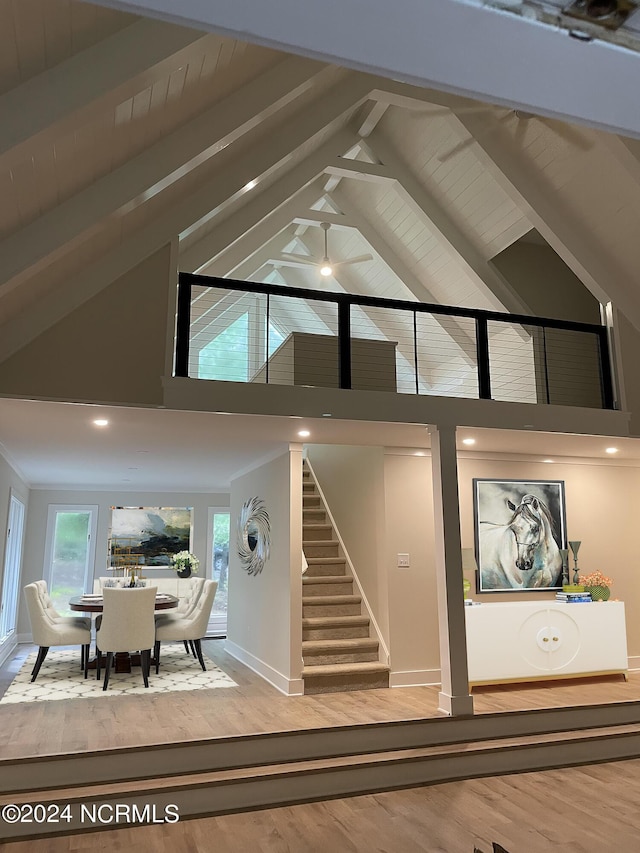 living room with beam ceiling, wood finished floors, high vaulted ceiling, baseboards, and stairs