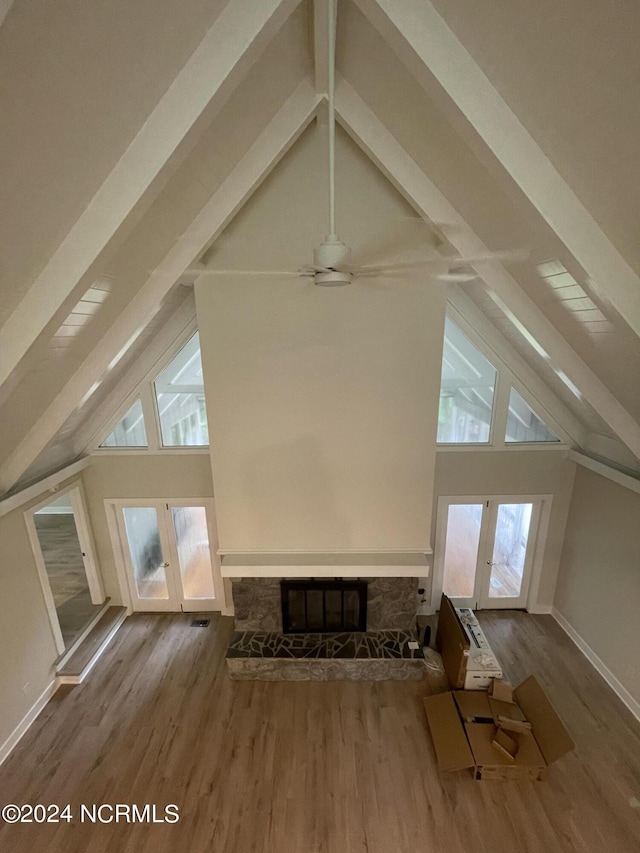 bonus room featuring beamed ceiling, high vaulted ceiling, french doors, and a fireplace