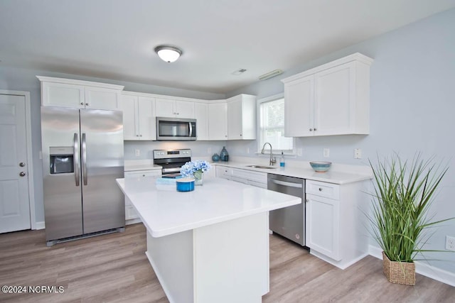 kitchen with appliances with stainless steel finishes, light wood-type flooring, a kitchen island, sink, and white cabinetry