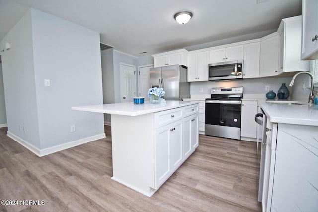 kitchen with a center island, white cabinets, sink, light hardwood / wood-style floors, and stainless steel appliances