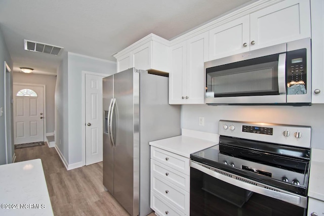 kitchen featuring white cabinets, ornamental molding, stainless steel appliances, and light hardwood / wood-style flooring