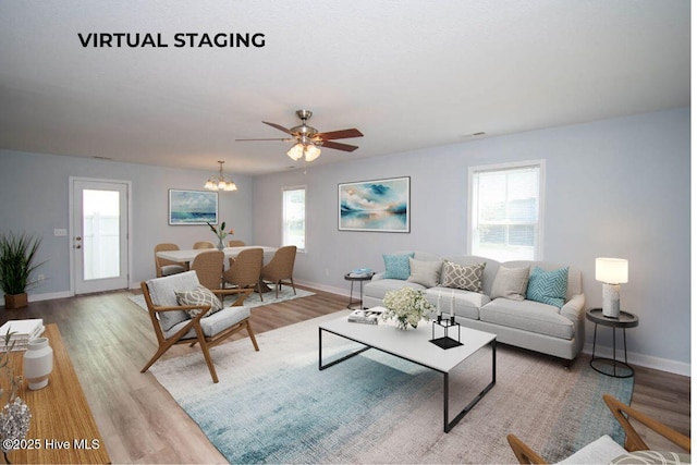 living room with light hardwood / wood-style flooring, a healthy amount of sunlight, and ceiling fan with notable chandelier