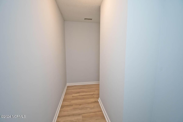 hall featuring light hardwood / wood-style floors and a textured ceiling