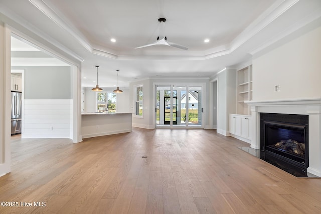 5037 Saltgrass Cv, Leland, NC 28451 - unfurnished living room with a tray ceiling, a fireplace, built in shelves, a ceiling fan, and light wood finished floors