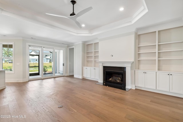 5037 Saltgrass Cv, Leland, NC 28451 - unfurnished living room with a tray ceiling, ceiling fan, baseboards, ornamental molding, and light wood-type flooring