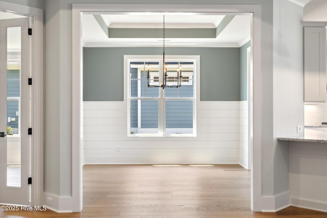 5037 Saltgrass Cv, Leland, NC 28451 - unfurnished dining area featuring a chandelier, a raised ceiling, wood finished floors, ornamental molding, and a wainscoted wall