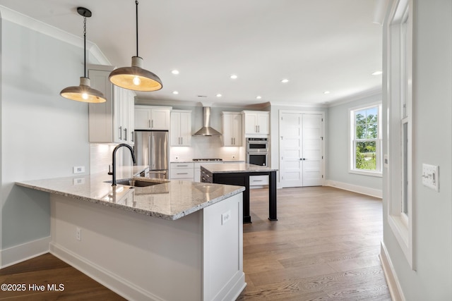 5037 Saltgrass Cv, Leland, NC 28451 - kitchen featuring wall chimney range hood, a sink, appliances with stainless steel finishes, decorative backsplash, and ornamental molding