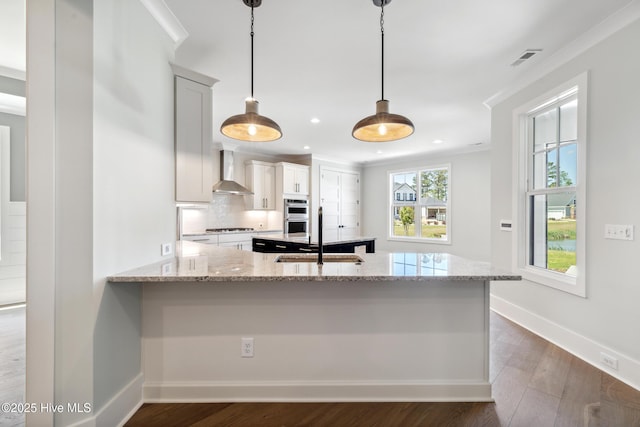 5037 Saltgrass Cv, Leland, NC 28451 - kitchen featuring a sink, wall chimney exhaust hood, gas stovetop, light stone counters, and crown molding