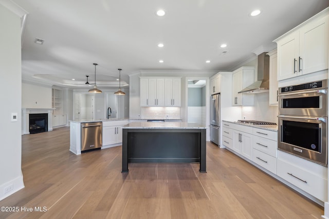 5037 Saltgrass Cv, Leland, NC 28451 - kitchen with wall chimney exhaust hood, appliances with stainless steel finishes, crown molding, backsplash, and white cabinets