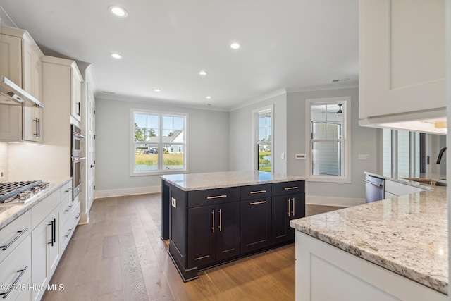 5037 Saltgrass Cv, Leland, NC 28451 - kitchen featuring a sink, crown molding, a center island, baseboards, and white cabinetry