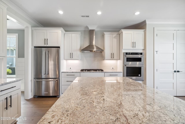 5037 Saltgrass Cv, Leland, NC 28451 - kitchen featuring stainless steel appliances, wall chimney exhaust hood, crown molding, white cabinets, and dark wood-style flooring