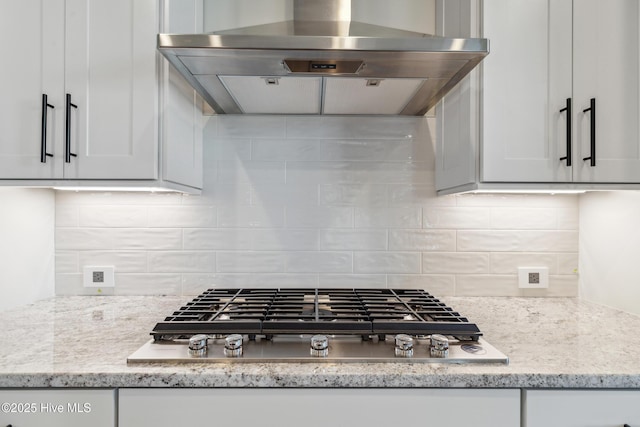 5037 Saltgrass Cv, Leland, NC 28451 - kitchen featuring ventilation hood, stainless steel gas cooktop, decorative backsplash, and white cabinetry