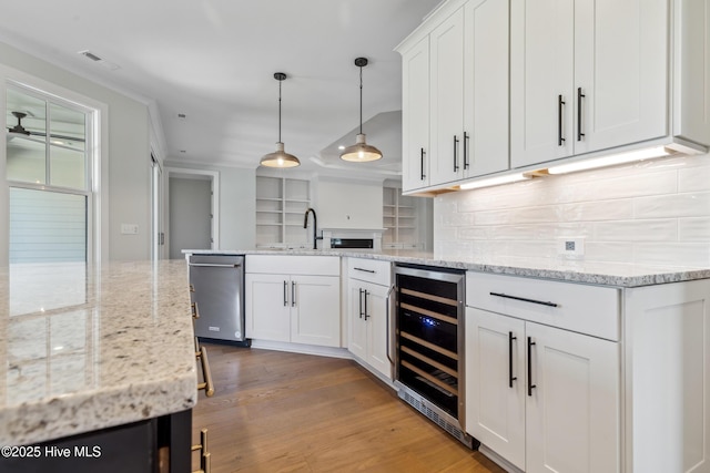 5037 Saltgrass Cv, Leland, NC 28451 - kitchen with wine cooler, stainless steel dishwasher, decorative backsplash, white cabinets, and light wood-style flooring