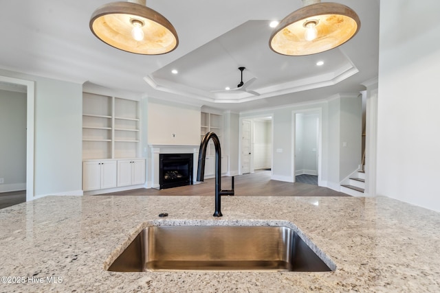 5037 Saltgrass Cv, Leland, NC 28451 - kitchen featuring a sink, a raised ceiling, open floor plan, light stone counters, and ceiling fan