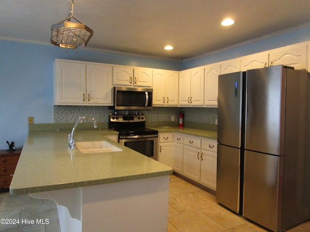 kitchen featuring crown molding, stainless steel appliances, white cabinetry, a sink, and a peninsula