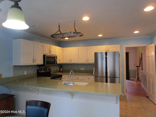 kitchen with a peninsula, white cabinets, stainless steel appliances, and a sink