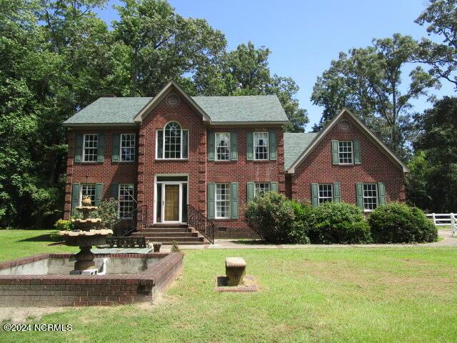 colonial inspired home featuring brick siding, crawl space, and a front yard