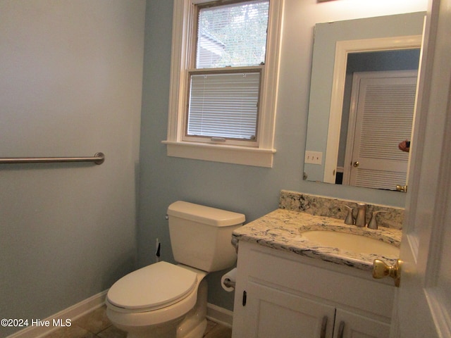 half bathroom with vanity, toilet, and baseboards