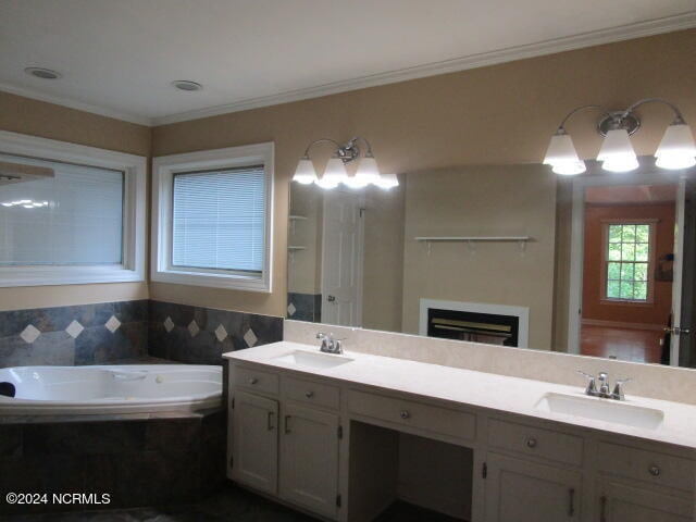 bathroom with crown molding, a fireplace, a sink, and a bath