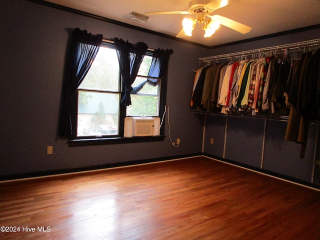 unfurnished bedroom featuring baseboards, ceiling fan, ornamental molding, wood finished floors, and cooling unit