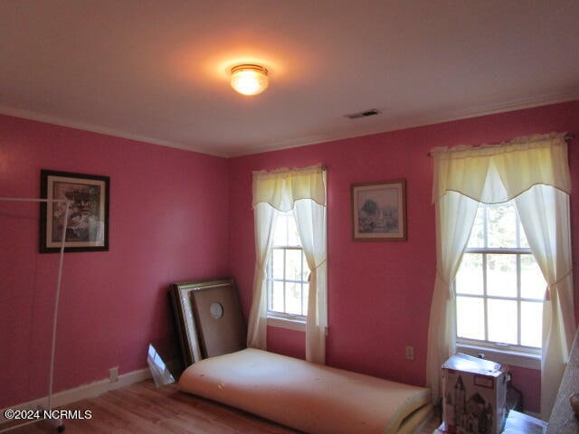 bedroom with visible vents, baseboards, and wood finished floors