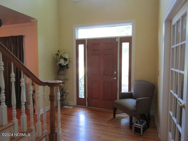 entrance foyer with stairway, wood finished floors, and baseboards