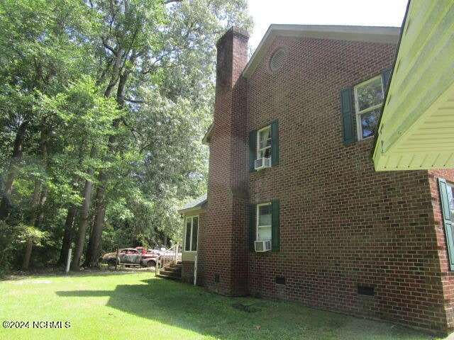 view of property exterior featuring crawl space, a chimney, a lawn, and brick siding