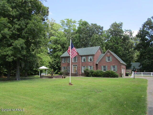 view of front of house featuring a front lawn, fence, and brick siding