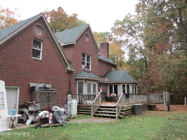 rear view of house featuring a shingled roof, brick siding, a lawn, and a chimney