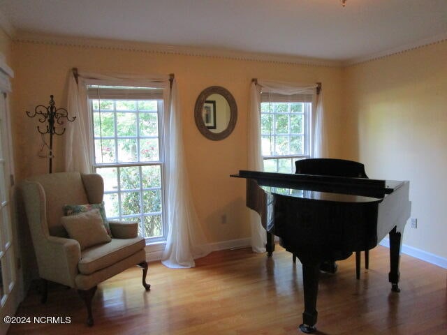 sitting room with ornamental molding, baseboards, and wood finished floors