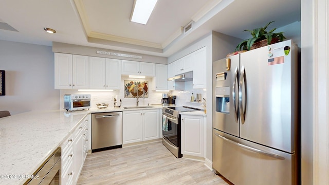 kitchen featuring light hardwood / wood-style flooring, light stone countertops, tasteful backsplash, stainless steel appliances, and white cabinets