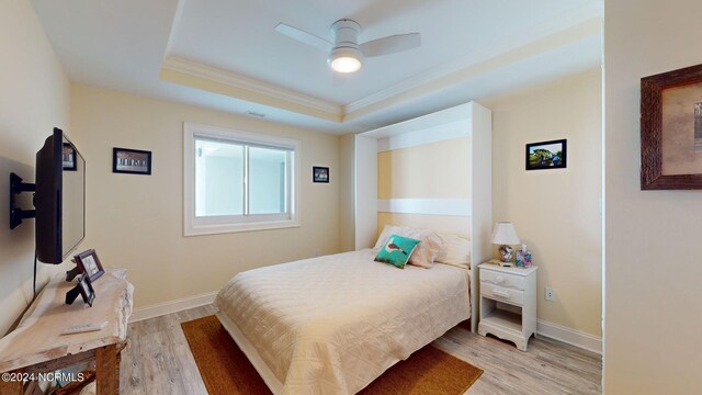 bedroom featuring light hardwood / wood-style flooring, ceiling fan, and a raised ceiling