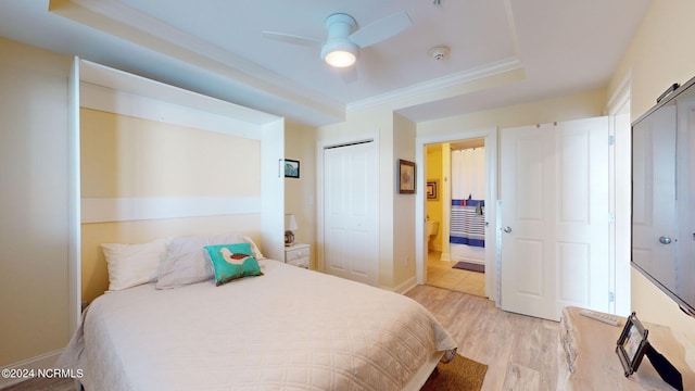 bedroom featuring ceiling fan, a raised ceiling, and light hardwood / wood-style flooring