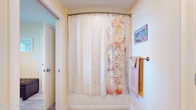 bathroom with hardwood / wood-style flooring and shower / bathtub combination with curtain