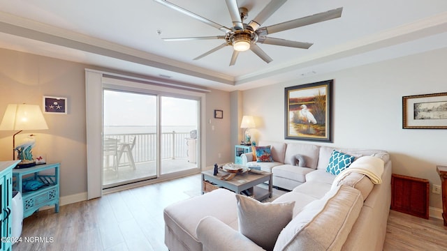 living room with ceiling fan, a raised ceiling, and light hardwood / wood-style floors