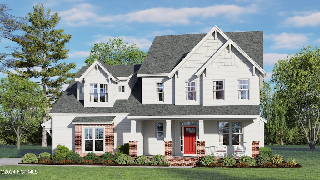 view of front of house with a porch, a front yard, roof with shingles, and brick siding