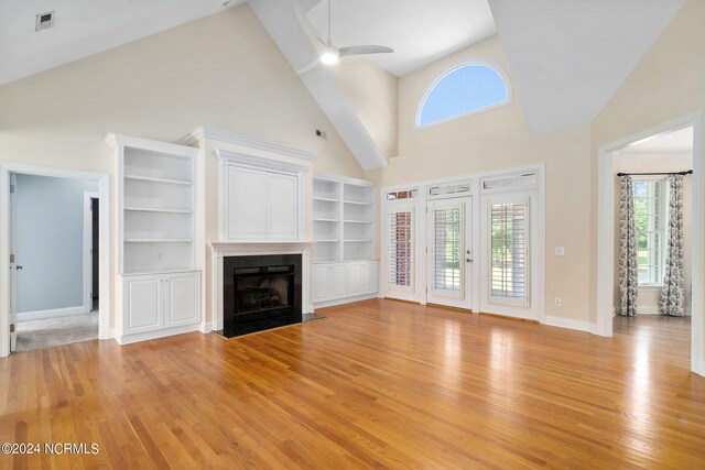 unfurnished living room featuring light wood-type flooring, plenty of natural light, a high end fireplace, and a ceiling fan