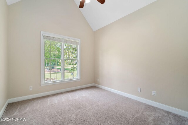 carpeted spare room with ceiling fan, high vaulted ceiling, and baseboards