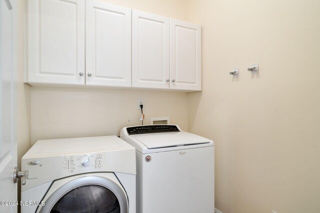 laundry area with independent washer and dryer and cabinet space