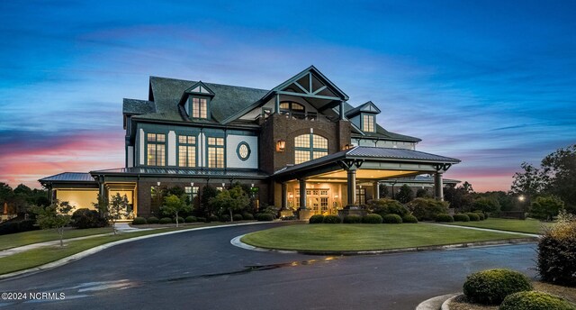 view of front of house featuring metal roof, aphalt driveway, and a front lawn